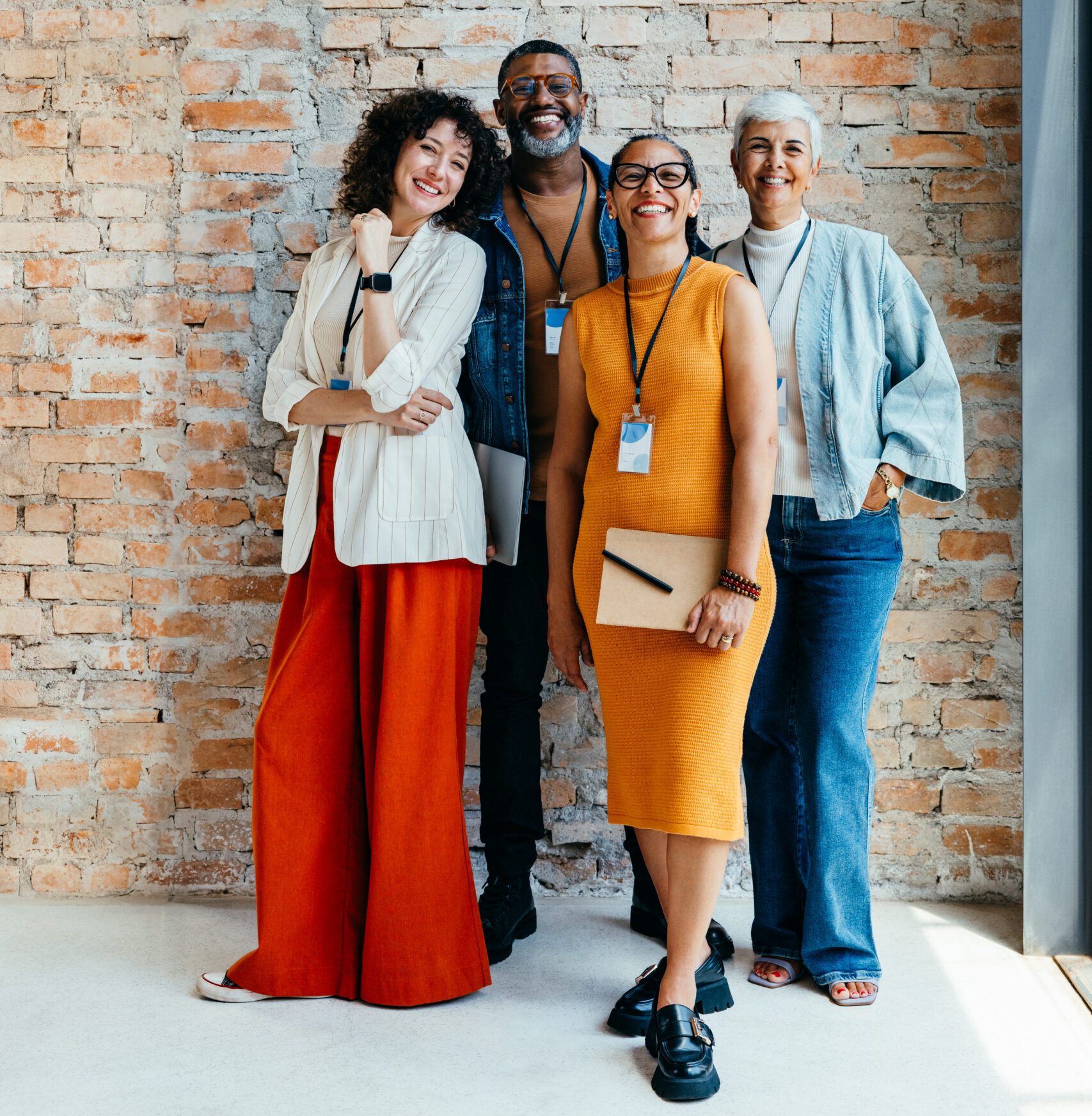 pr-firm_24 A group of confident, diverse coworkers standing together against a rustic brick wall in a modern office setting, showcasing teamwork and camaraderie.
